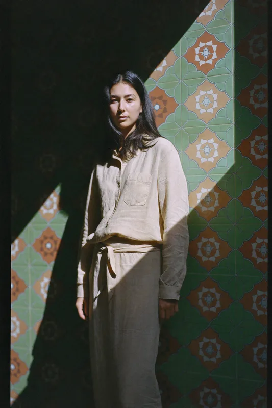 Lalang — editorial portrait in oat linen against a Peranakan tile wall in hard midday sun